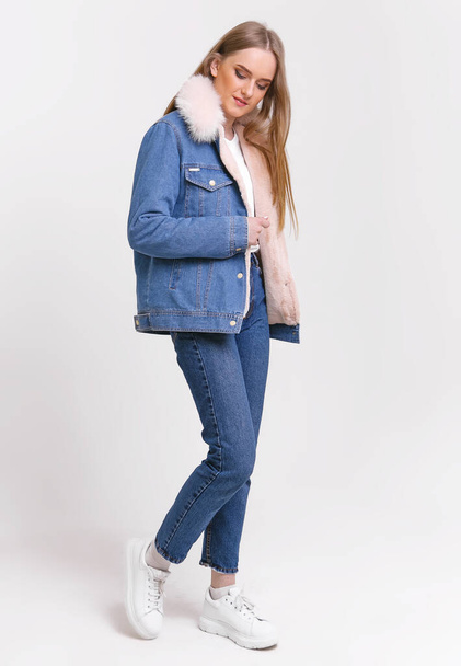 Young Woman in a denim suit with a fur collar on a white background. Clothing advertising concept. - Zdjęcie, obraz