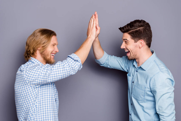 Profile side view portrait of two nice attractive glad cheerful cheery guys best buddy fellow clapping palms deal done success team isolated over gray purple pastel color background - Фото, изображение
