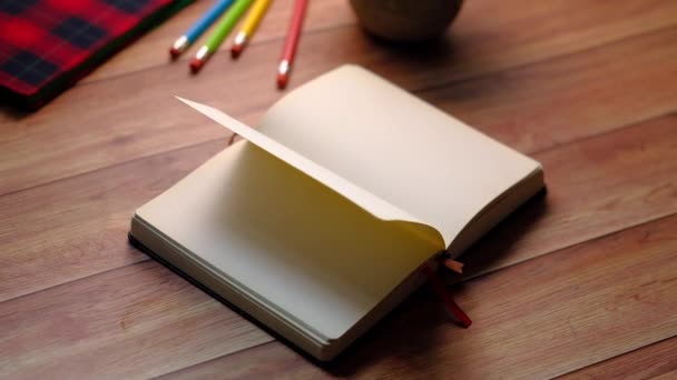 otevřená kniha a tužka na dřevěném stole  - Záběry, video