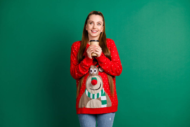 Photo of funny attractive lady hold hands hot coffee to go shop beverage look up empty space dreamer newyear mood atmosphere wear red ugly pullover isolated green color background - Fotografie, Obrázek