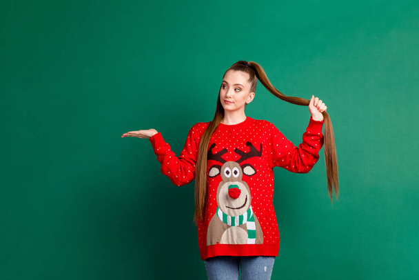 Portrait of her she nice-looking attractive pretty content long-haired girl holding on palm copy empty blank place space choose choice holding ponytail isolated over green color background - Zdjęcie, obraz