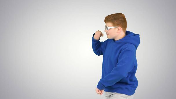 Cool boy dancing while walking by on gradient background. - Φωτογραφία, εικόνα