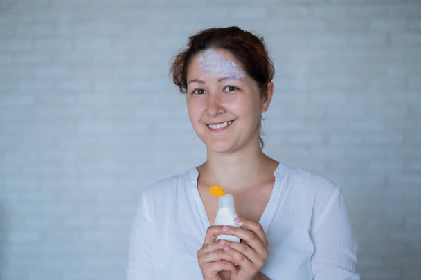 Portrait of a Caucasian woman with vitiligo diseas uses sunscreen - Photo, Image