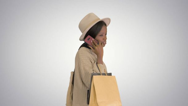 African american girl in oversized knitwear and hat talking on h - Foto, afbeelding