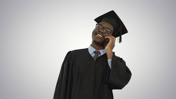 Smiling african american male student in graduation robe talking - Фото, изображение