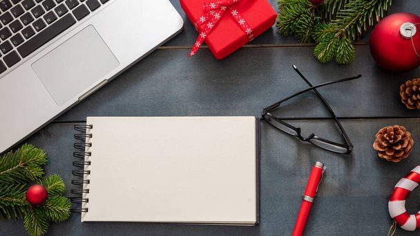 Різдво, офіс зачинено. Бізнес-стіл плоский, шаблон святкової картки. Порожня блокнот, ноутбук та різдвяні прикраси на синьому фоні, вид зверху, простір для копіювання
. - Фото, зображення
