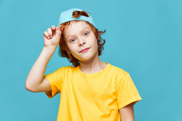 Cheerful redhead boy in blue cap yellow T-shirt fashionable clothes isolated he  - Fotó, kép
