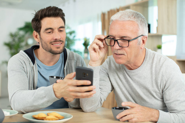 joyful elderly man and son talking on smartphone - Zdjęcie, obraz