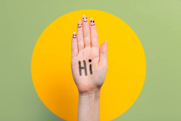 A világ köszöntő napja. Emelt női kéz a felirattal Hi. Zöld, sárga golyós háttérrel. Fénymásolási hely. - Fotó, kép