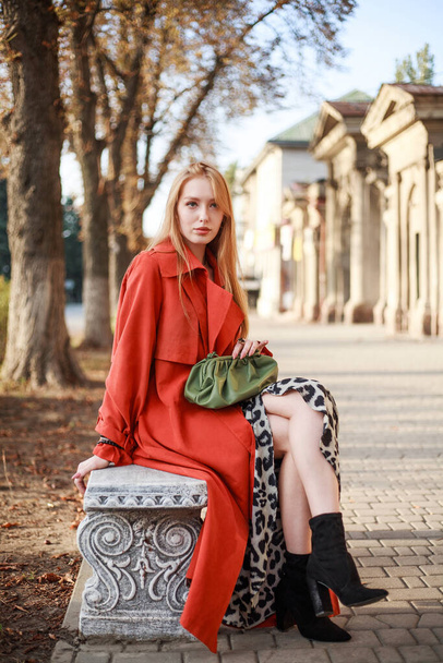 Elegant woman in a terracotta coat on the street of an old European city - 写真・画像
