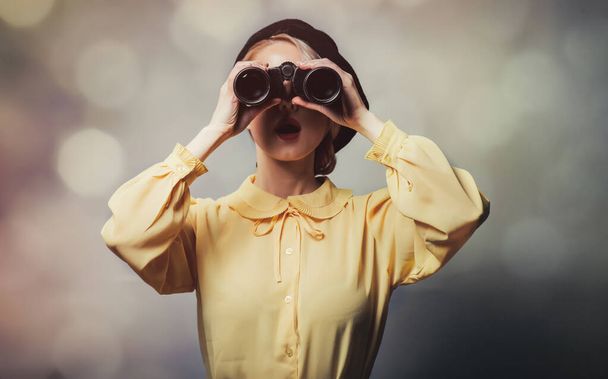 Beautiful girl in vintage clothes with binoculars on gray background - Foto, immagini