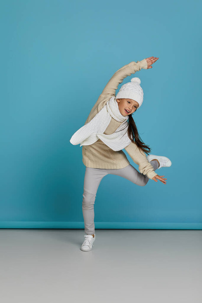 little child girl in winter knitted hat and sweater jumping - Foto, imagen