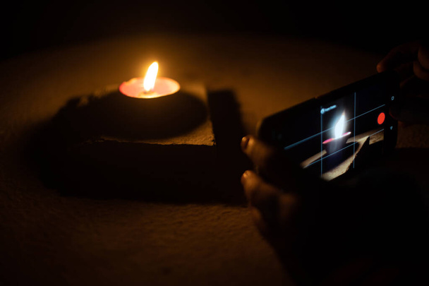 Мужчина женщина делает низко светлые фотографии diya лампы масла с мобильным телефоном для обмена изображениями на индуистском фестивале diwali - Фото, изображение