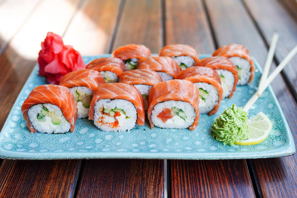Sushi z Philadelphia roll z łososiem, krewetkami, awokado, serem śmietankowym. Menu z sushi. Jedzenie japońskie. - Zdjęcie, obraz