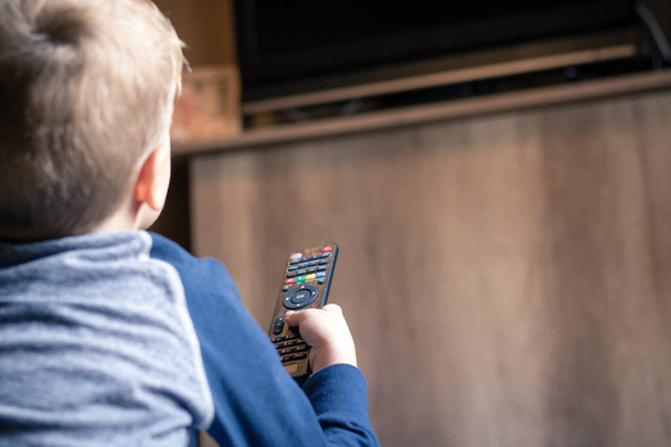 Kind fernsehen und Sender wechseln mit Fernbedienung.  - Foto, Bild