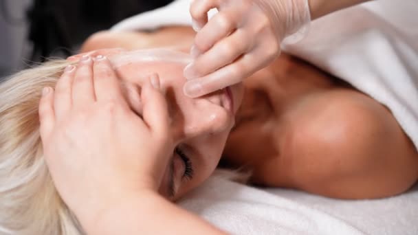 Mulher massagista faz rosto relaxante massagem e cavidade oral para jovem bela cliente loira. Tratamento de spa para a pele perfeita no salão de beleza. Serviços de Cosmetologia. Saúde e medicina - Filmagem, Vídeo
