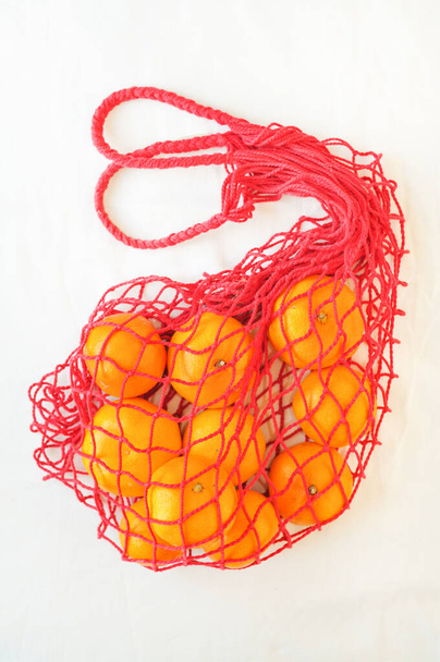 orange tangerine in red handbag on white background - Foto, imagen