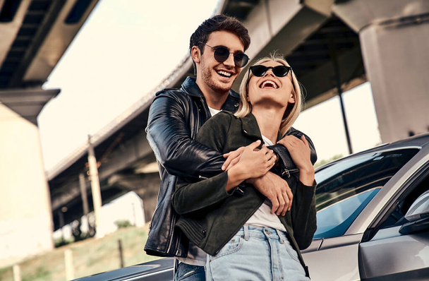 Beautiful young couple in casual clothes near sport car. - Фото, изображение