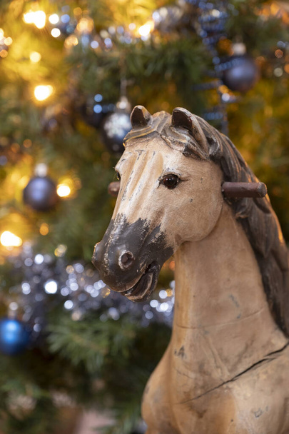 Schönes Detailfoto von einem hölzernen Schaukelpferd und einem Teil eines Weihnachtsbaums. Weihnachten 2020. - Foto, Bild