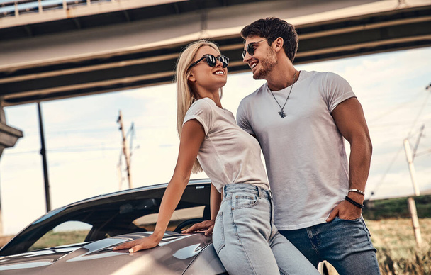 Beautiful young couple in casual clothes near sport car. - Fotoğraf, Görsel