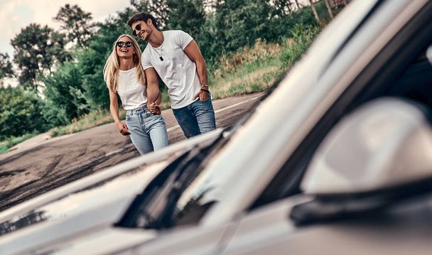 Beautiful young couple in casual clothes near sport car. - Foto, imagen