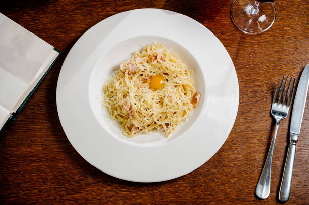 spaghetti with cheese and egg on a white plate on wooden background - Foto, immagini