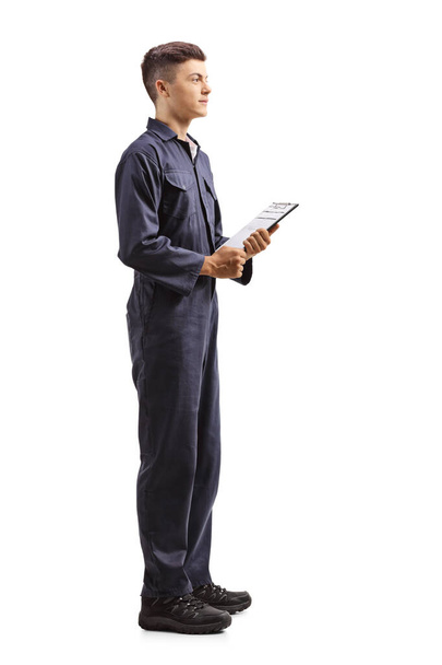 Full length portrait of a young mechanic worker in a uniform holding a clipboard isolated on white background - Foto, immagini