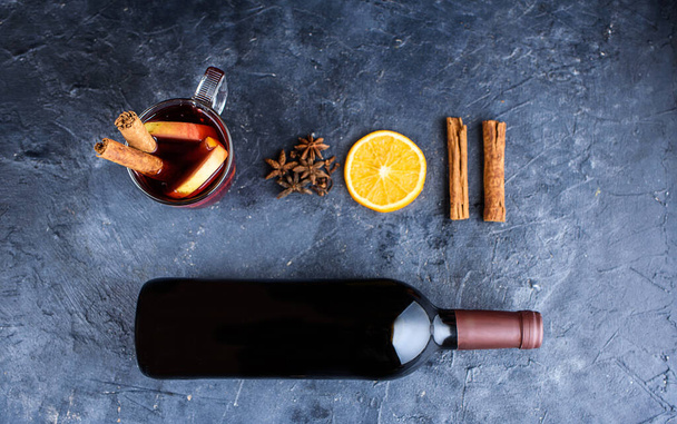 Mulled wine recipe ingredients on black chalkboard with text space - christmas or winter warming drink. Bottle of wine, honey, orange, cinnamon sticks, anise, nutmeg. Winter content - Photo, Image