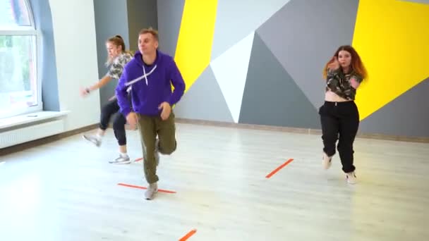Een man en twee vrouwen dansen hip hop, een vrije stijl jeugd hedendaagse dans in een dansstudio. - Video