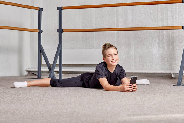 A man is lying on the floor, legs apart. Flexibility and endurance training. - Фото, изображение