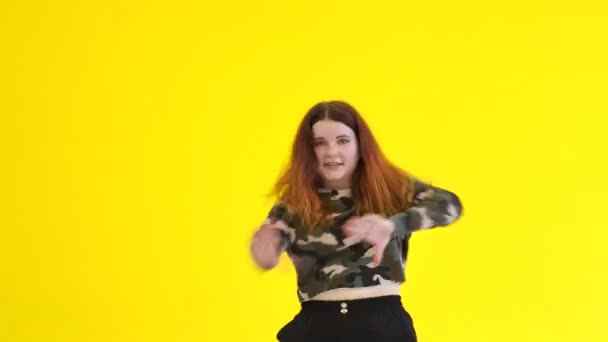 Jonge energieke vrouw dansend moderne jeugd dans vrije stijl in de studio tegen de achtergrond van een gele muur. Geïsoleerd. Middellange termijn - Video