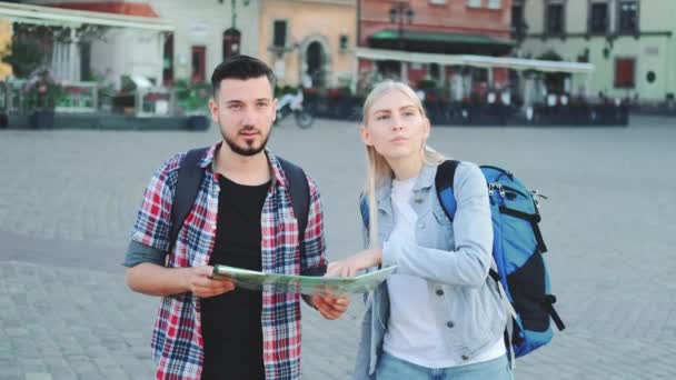 Pareja joven de turistas con mapa en busca de nuevo lugar histórico en el centro de la ciudad - Metraje, vídeo