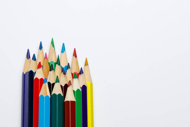 Vooraanzicht van kleurpotloden in verschillende kleuren met de pen tips op witte uniforme achtergrond, educatieve afbeelding of gebruik voor creatieve presentatie - Foto, afbeelding