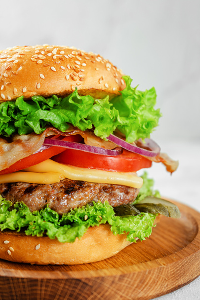 Nahaufnahme eines hausgemachten Burgers auf einem Holzteller. Fastfood-Konzept. - Foto, Bild