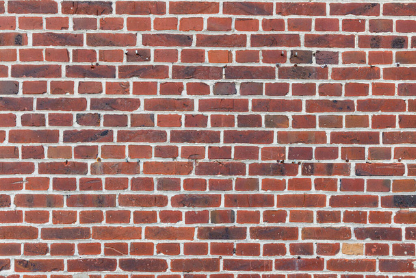 Textura de pared de ladrillo rojo con ladrillos erosionados y pequeños agujeros y golpes, uso como textura del activo del juego o fondo de pantalla - Foto, Imagen