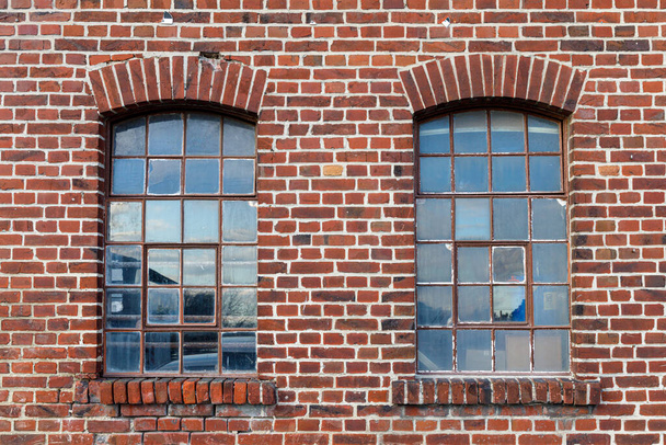 Два промислових вікна з розбитими шматочками глазурі, віконна рама іржавіє, цегляна стіна вивітрюється з багатьма недоліками. Використовувати як посилання на текстуру ігрового активу
. - Фото, зображення