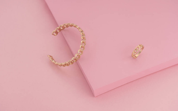 Chain shape Golden ring and bracelet on pink color background - Foto, afbeelding