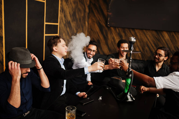 Group of handsome retro well-dressed man gangsters spend time at club, smoking hookah. Multiethnic male bachelor mafia party in restaurant. - Фото, зображення