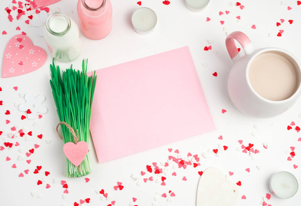 Fond romantique avec des cœurs, tasse de café, enveloppe rose et un bouquet d'herbe sur un fond clair. - Photo, image