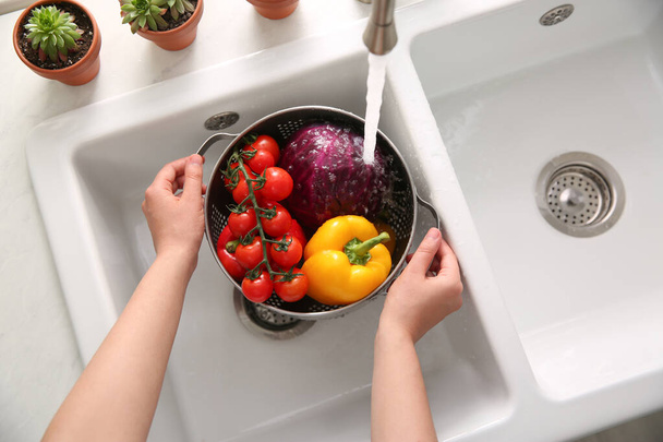Woman washing fresh vegetables in kitchen sink, top view - Photo, image
