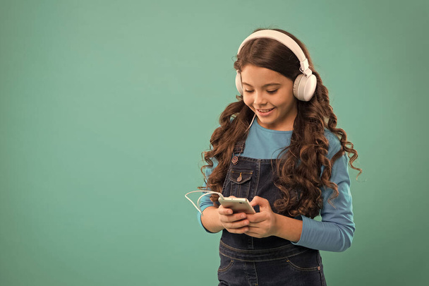 Online entertainment. Free music apps. Listen for free. Get music account subscription. Enjoy music concept. Enjoy perfect sound. Small girl child listen music modern headphones and smartphone - Foto, Imagem