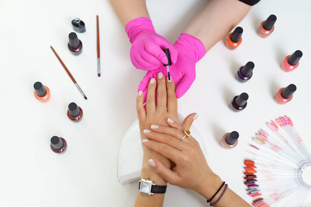 Манікюрник лікує клієнта в салоні краси нігтів. Манікюр, малюнок на нігті
 - Фото, зображення