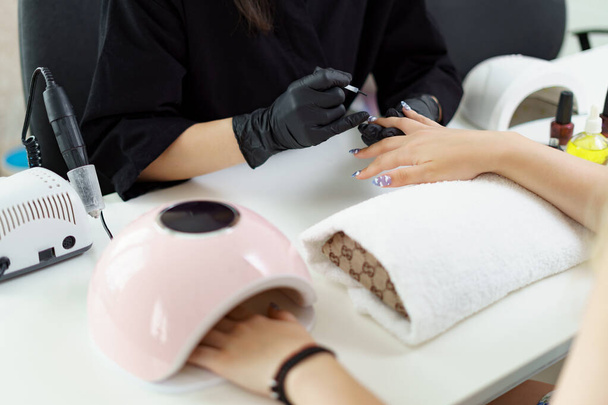 Manicurist treating client at beauty nails salon. Manicure, painting on nail - Photo, Image