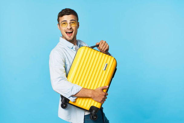 Мужчина в очках с чемоданом в руках с широко раскрытым ртом смотрит вперед  - Фото, изображение