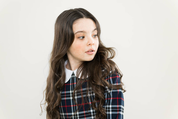 small girl classy checkered dress. kid fashion concept. take care about her hair. child has long curly hair. after visit to hairdresser. schoolgirl in stylish uniform. back to school - Фото, зображення