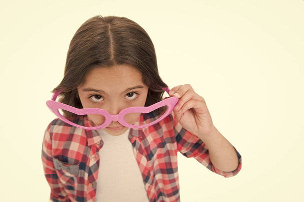 Who are you. Schoolgirl heart shaped glasses isolated white background. Child serious girl picking out of eyeglasses copy space. Child smart kid wondering face close up. Suspicious concept - Valokuva, kuva