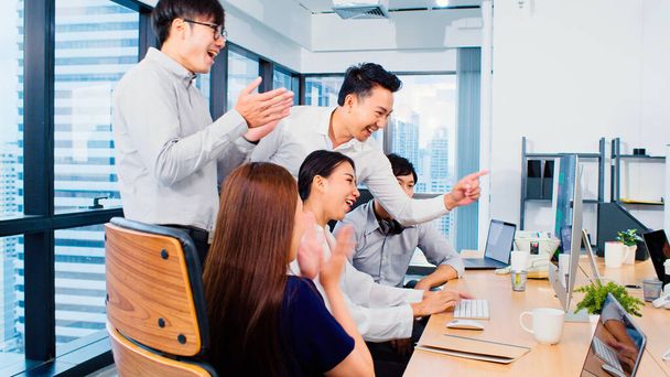 Group of Asian business people work together in team brainstorm discussion, clap hand celebrate in office. Corporate business, coworker teamwork, or success project meeting concept - Photo, Image