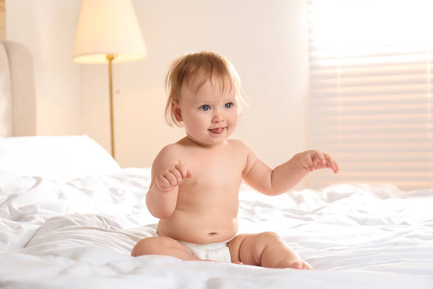 Cute little baby in diaper sitting on bed - Фото, зображення