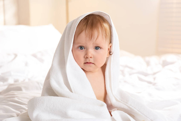 Cute little baby with soft towel on bed after bath - Foto, imagen