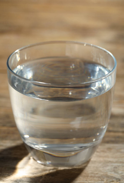 Glass of water on wooden table, closeup. Refreshing drink - Photo, image